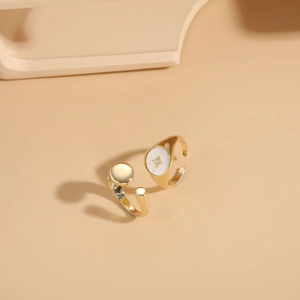 Detail of gold rings with white inlay and star motif on beige display background