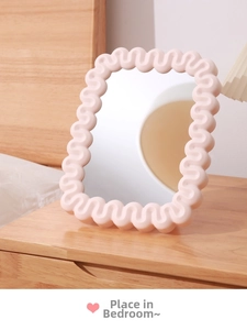 Detailed view of the wavy cream-colored frame and high-definition surface of this makeup mirror
