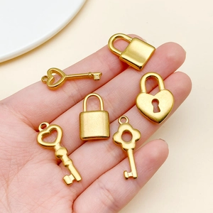 Close-up of six gold stainless steel heart-shaped lock and key charms held in hand