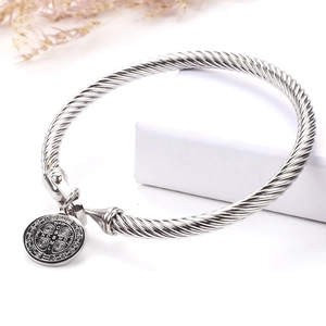 Twisted stainless steel bangle with St. Benedict religious medal charm on white background