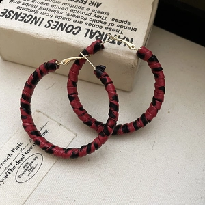 Détail de créoles enveloppées de cuir rouge et noir avec cadre en métal doré