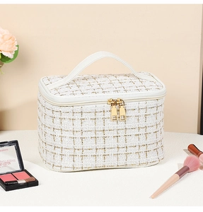 Detailed view of white tweed makeup bag with gold thread and dual metal zippers