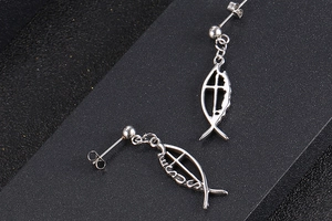 Macro detail of silver titanium fish earring featuring a cross and Jesus lettering