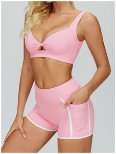 Dettaglio del reggiseno sportivo rosa con nodo e pantaloncini a vita alta con tasca laterale