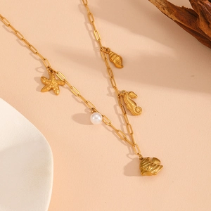 Detail of golden paperclip chain necklace with starfish shell and pearl pendants