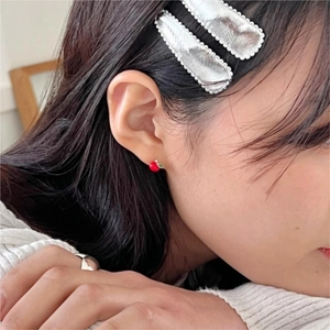Close-up of a 925 sterling silver red apple stud earring worn by a model