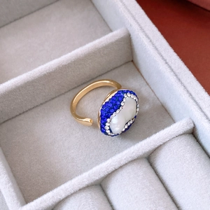 Detailed view of an 18k gold plated ring with blue crystals and pearl in a velvet box