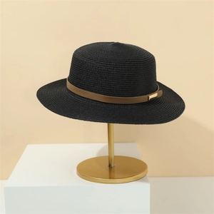 Detail of a black woven straw hat with brown leather band and gold buckle on a stand