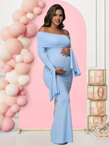 Close-up of light blue off-shoulder maternity dress set against a pink party backdrop