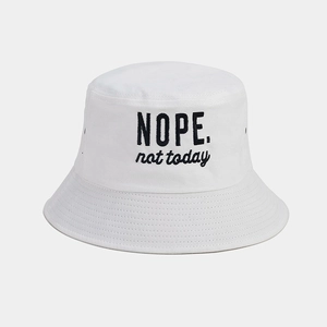 Close-up of cotton sun hat featuring black NOPE not today embroidery on white fabric