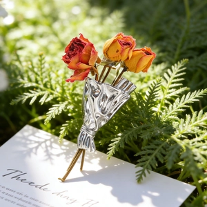 Elegant rose bouquet brooch with red dried flowers and silver metal on a white card