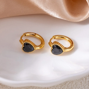 Close-up of gold-plated heart hoop earrings featuring black zircon stones on silk fabric