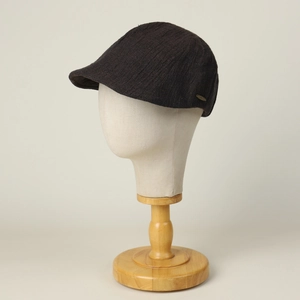 Retro linen flat cap in dark brown featuring a textured pleated fabric and metal logo