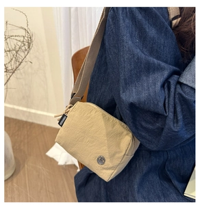 Dettaglio della borsa a tracolla in nylon beige con logo argento e cinturino