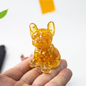Macro shot of a mini French Bulldog resin figurine with gold foil flakes in hand