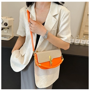 Detail of two-tone crossbody box bag with orange leather and beige woven flap texture