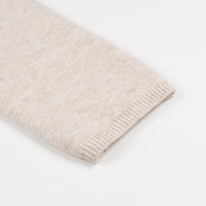Close-up of oatmeal knit cardigan showing ribbed cuffs and fine woolen fabric texture