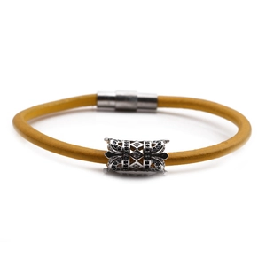 Detail of yellow braided leather bracelet with silver zircon charm and magnetic buckle