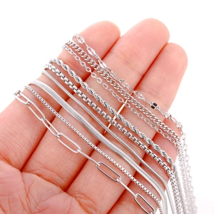 Various silver stainless steel jewelry chain styles shown in a person's hand