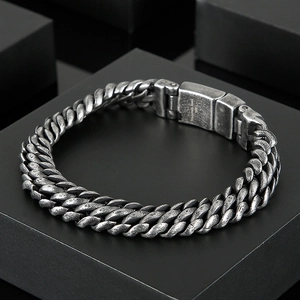 Retro stainless steel mesh chain bracelet for men displayed on a black geometric stand