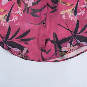Dettaglio dell'orlo rotondo e della stampa floreale su una camicia a maniche lunghe magenta