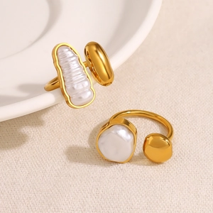 Macro detail of two gold irregular pearl rings on white ceramic plate background