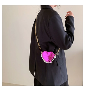 Détail d'un mini sac à bandoulière en forme de cœur magenta avec chaîne dorée