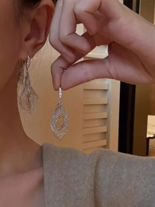 Detail of layered silver hollow leaf earrings with sparkling cubic zirconia hooks