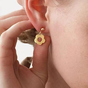 Close-up of elegant gold flower drop earrings worn by a model for a refined minimalist look