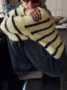 Detailed texture of a plush yellow and black striped knit sweater for women