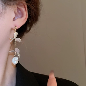 Close-up of floral tassel earrings with baroque pearls and matte petals on a model