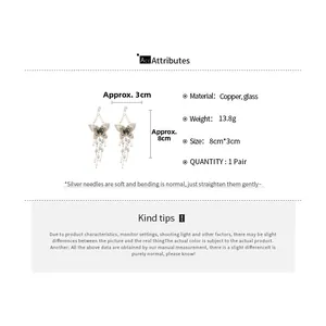 Détail des boucles d'oreilles papillon à pompons avec dimensions de 8 cm sur 3 cm