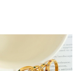 Close-up of gold multi-layer rings with colorful zircons on a white ceramic rim