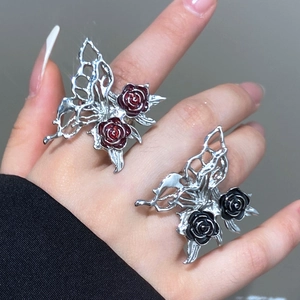 Macro detail of gothic hollow butterfly rings featuring dark red and black roses
