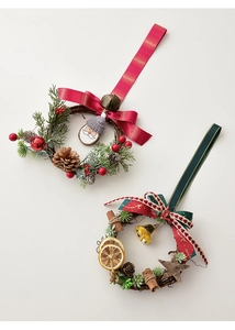 Detailed view of handmade Christmas wreaths with pine cones, red berries, and bells