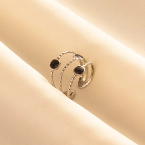 Macro shot of silver-tone triple-layered ring with black enamel inserts on satin