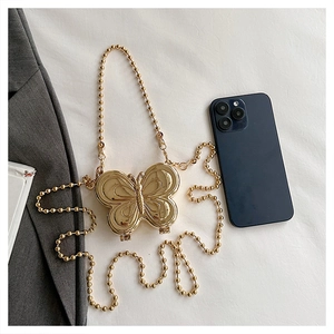 Detailed shot of golden butterfly mini bag next to a smartphone for size reference