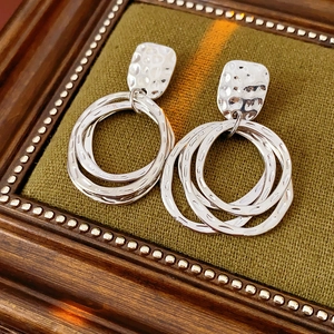 Macro shot of silver geometric interlocking circle earrings on a green fabric base