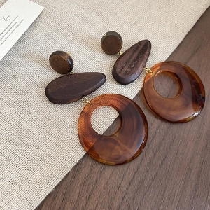 Detailed view of wood and amber resin drop earrings on a rustic linen background