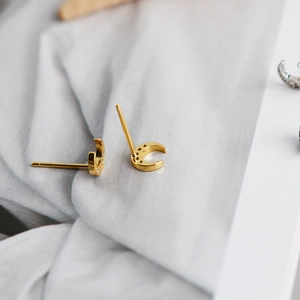 Macro shot of gold moon earrings with zircon inlay showing polished metal surface