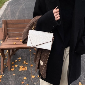 Detail der weißen Umschlagtasche mit silbernen Pailletten und Goldkette in Herbstszene