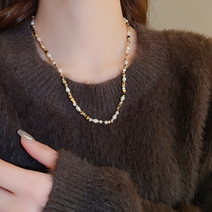 Detail of freshwater pearl and agate beaded necklace on a brown winter sweater