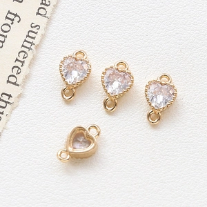 Detailed macro view of four gold plated heart connectors with sparkling zircon stones