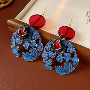 Detail of vintage flower earrings with blue enamel, gold finish, and red resin accents