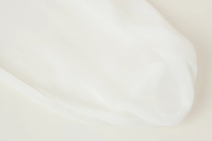 Close-up detail of white mesh fabric texture and ruffled edges on this V-neck blouse