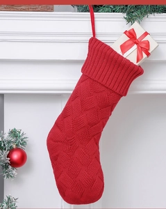 Detail of red cable knit Christmas stocking with hanging loop and white gift box