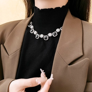Détail d'un collier de luxe carré avec pierres noires et cristaux pavés sur un mannequin