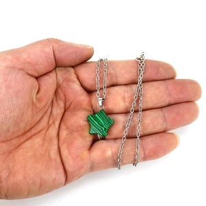 Pentagram necklace with green malachite crystal star pendant and silver chain held in hand
