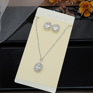 Detail view of silver necklace and earring set with claw-set zircon on display card