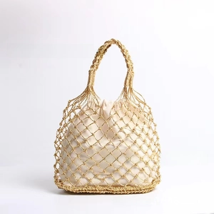 Detail einer handgewebten goldenen Netztasche mit cremeweißem Kordelzugfutter für Urlaub